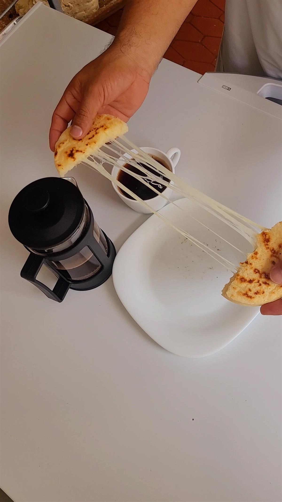 Arepa NATCASA con queso fundido, servida junto a café